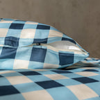 Blue and white checkered pillow and bedding on a neutral background