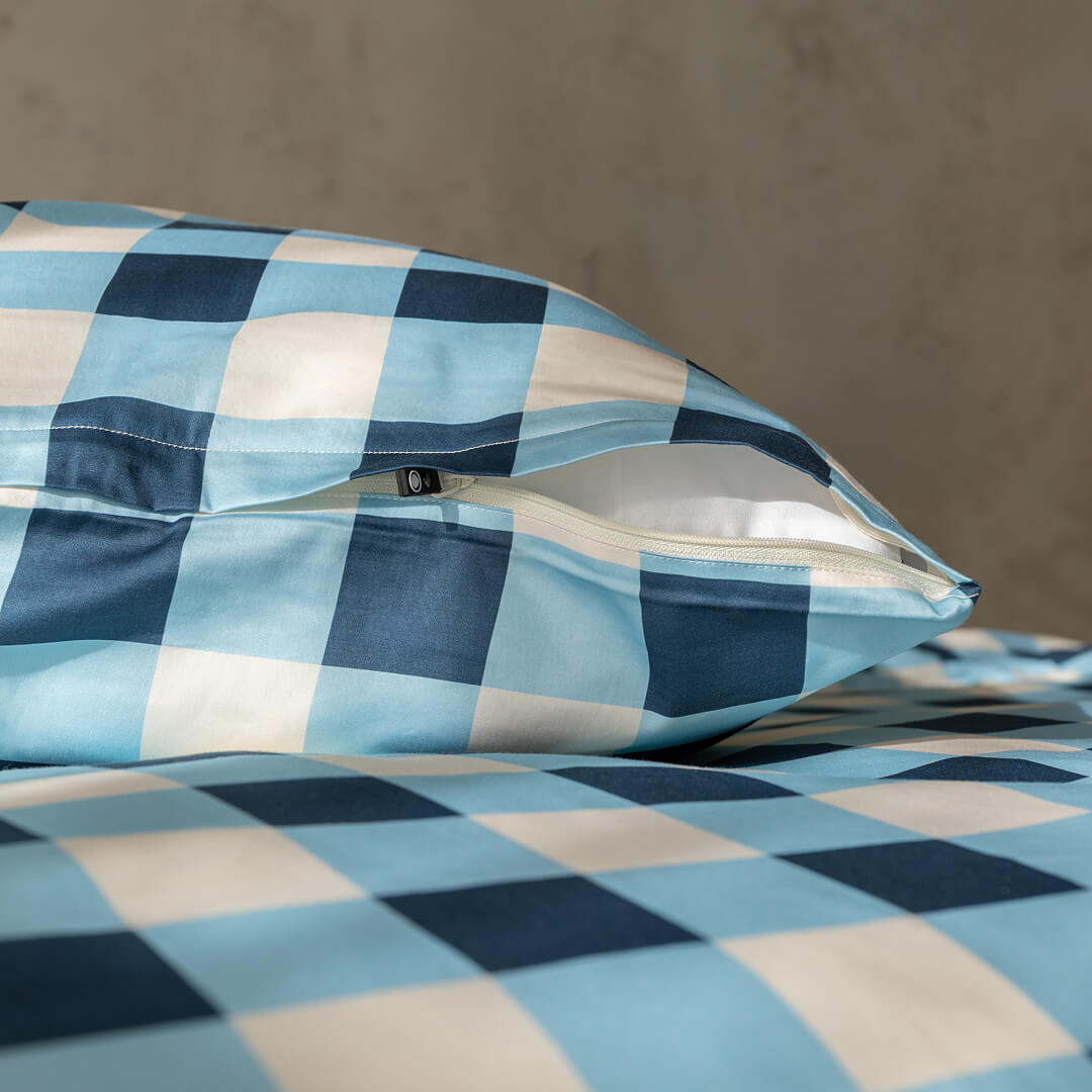 Blue and white checkered pillow and bedding on a neutral background
