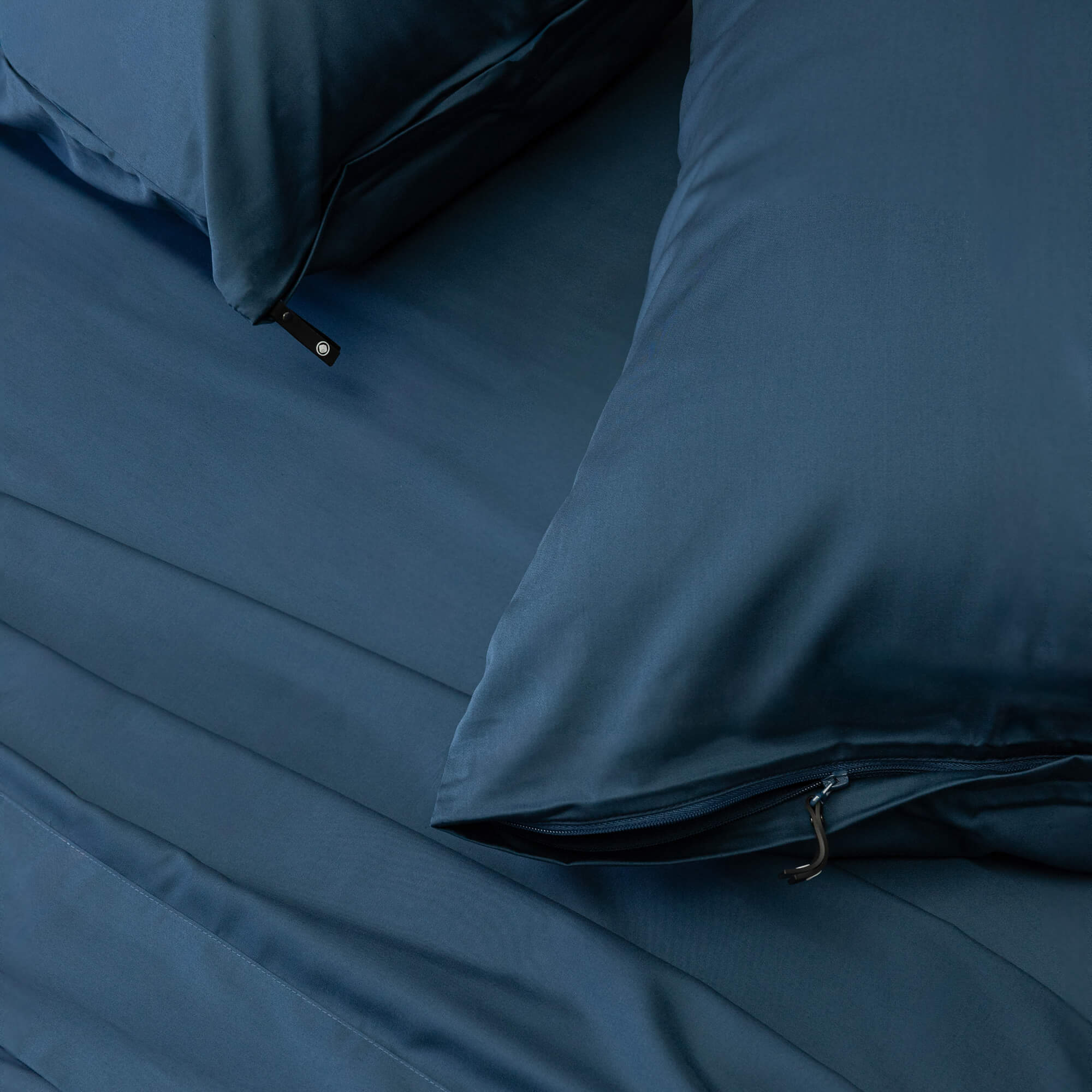 Blue bedding set with pillows and fitted sheet on a bed.
