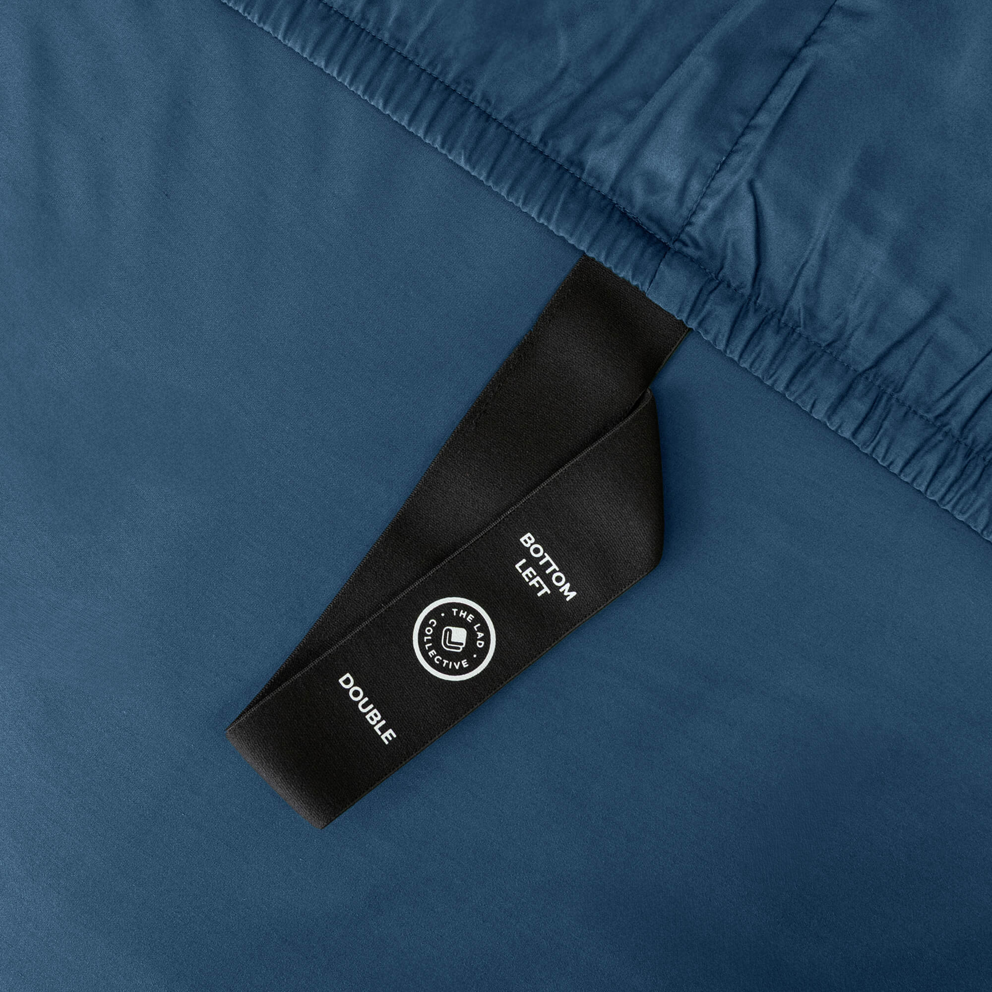 Close-up of a blue fitted sheet with a black label on a matching fabric background.