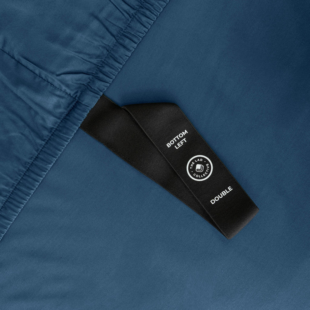 Close-up of a blue fitted sheet with a black label on a matching fabric background.