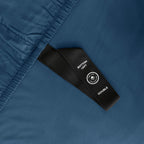 Close-up of a blue fitted sheet with a black label on a matching fabric background.