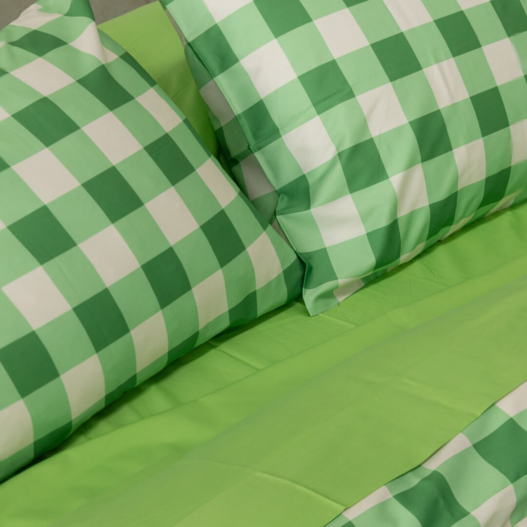 Meadow green gingham print duvet cover set on a bed. Close up of the pillowcases against a contrasting green sheet set.