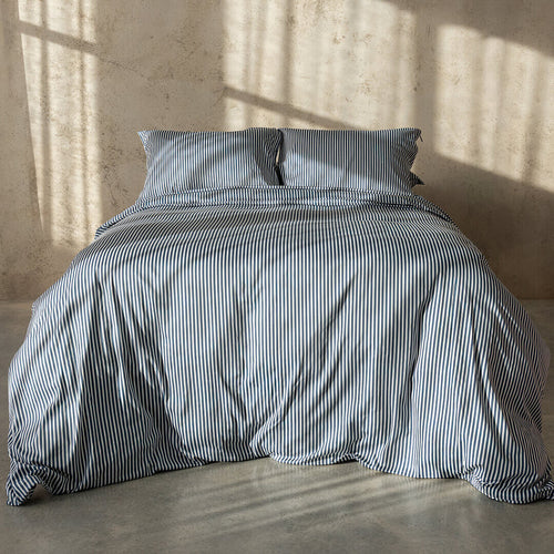 Navy and white pinstripe duvet cover on bed with neutral background.