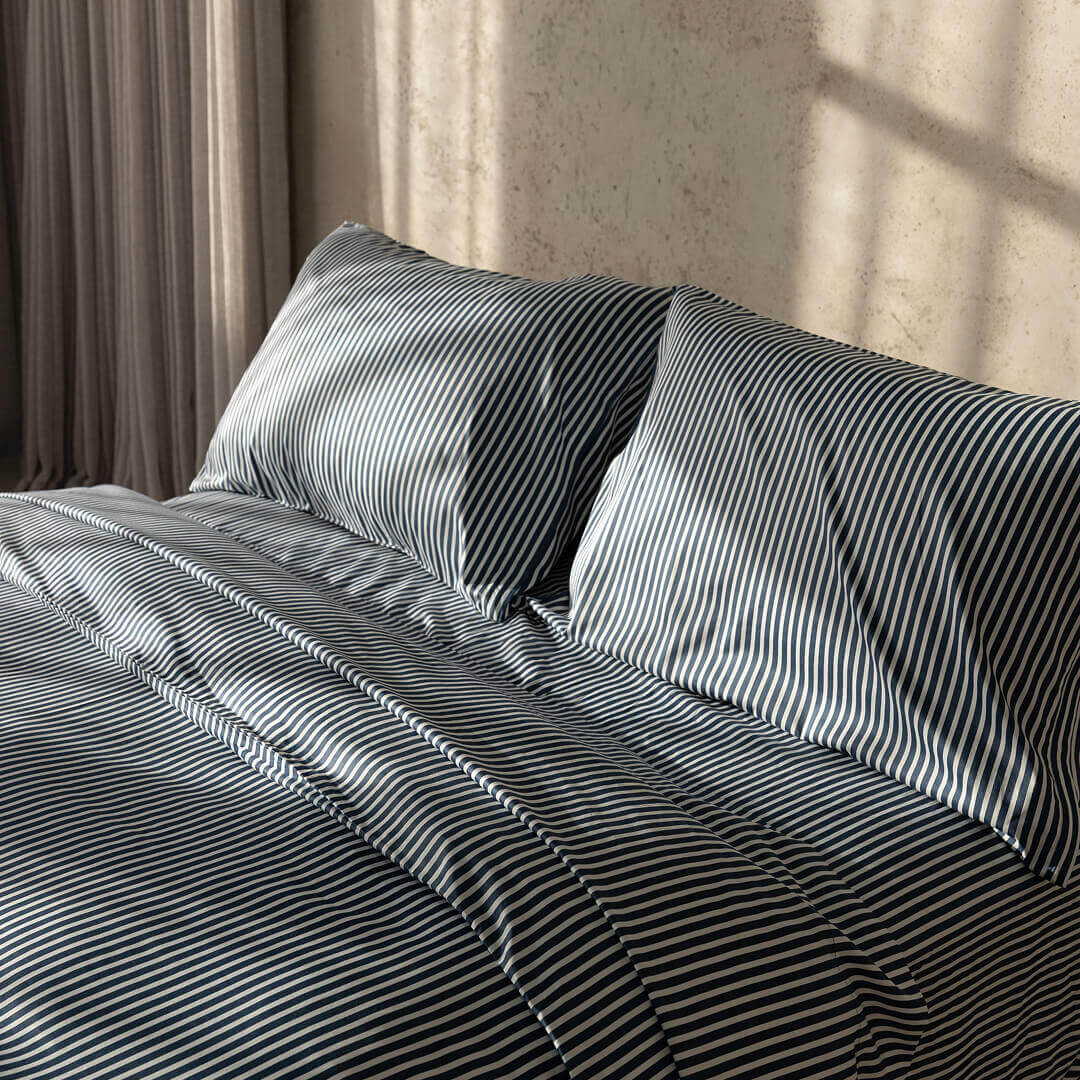 Navy and white pinstripe duvet cover on bed with neutral background.