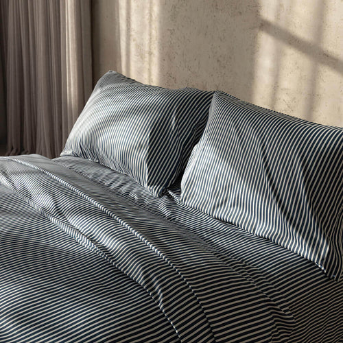Navy and white pinstripe duvet cover on bed with neutral background.