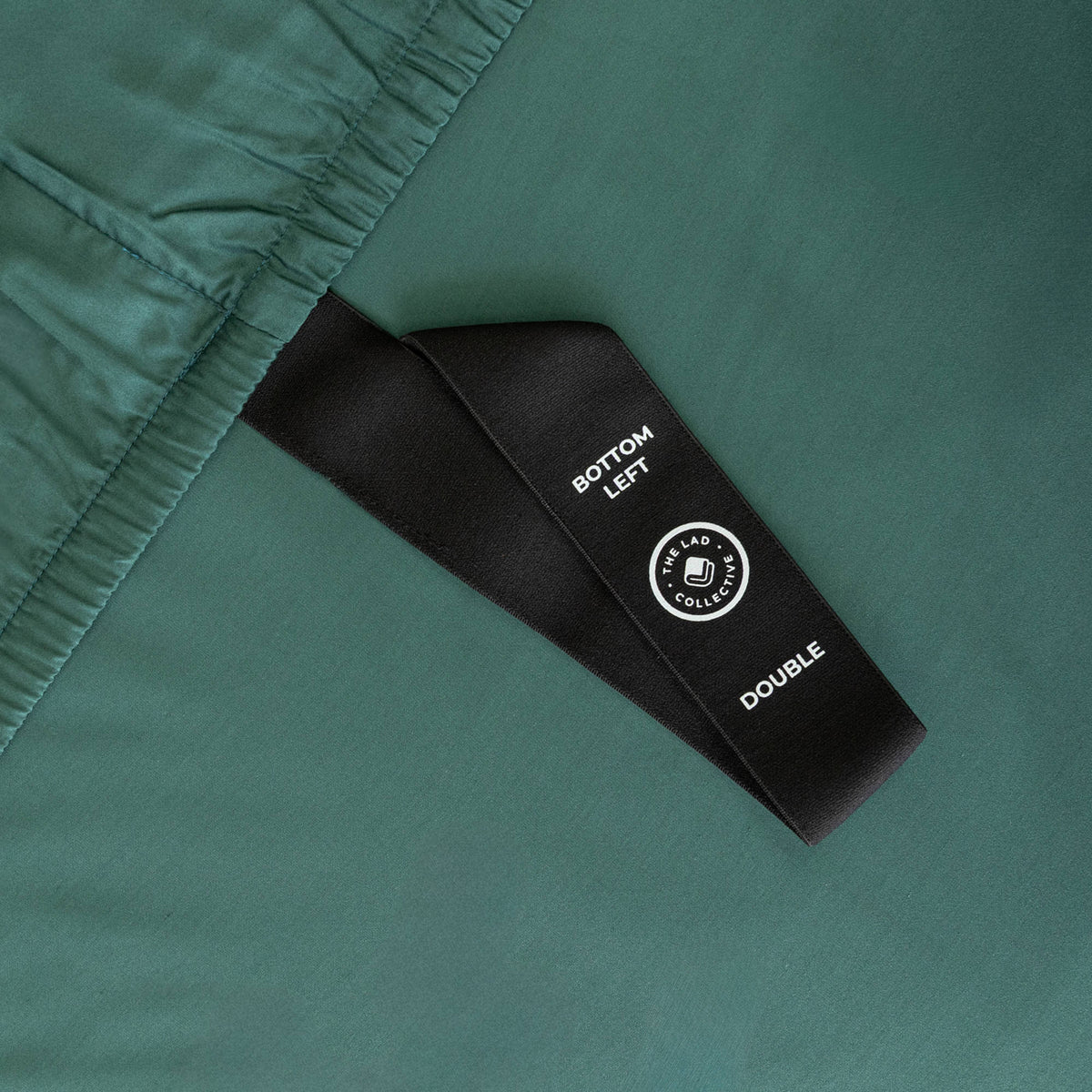 Green bedspread on a bed with matching pillows against a beige curtain background