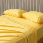 Close-up of bright yellow bedding set on a bed, against a beige curtain. 
