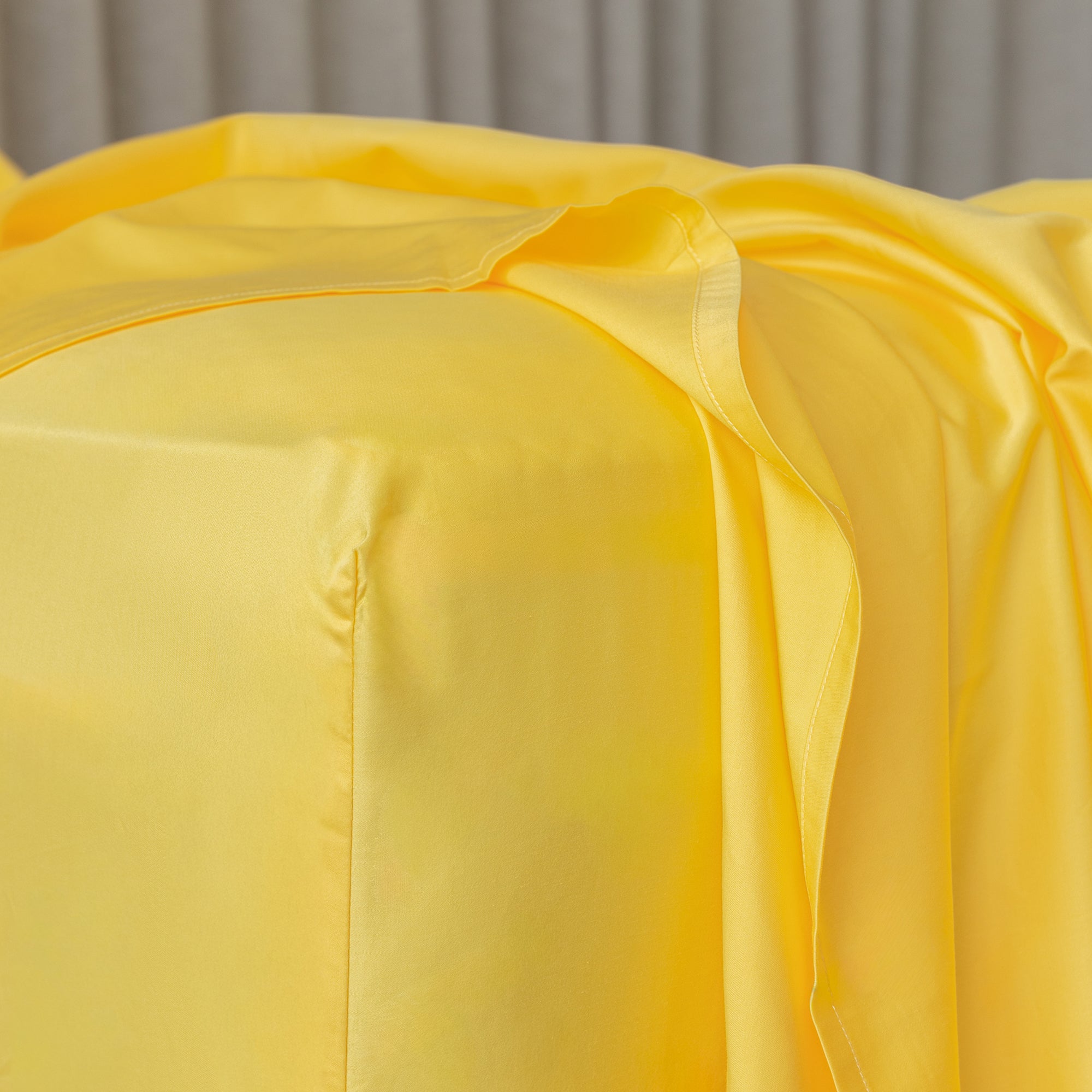 Close-up of bright yellow fitted sheet on corner of the bed.