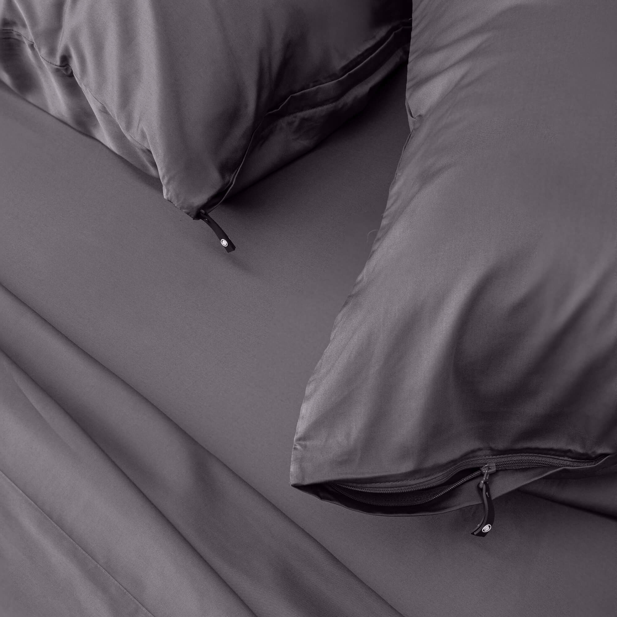 Close up of pillows and pillowcases with zip detail in dark gray bedding
