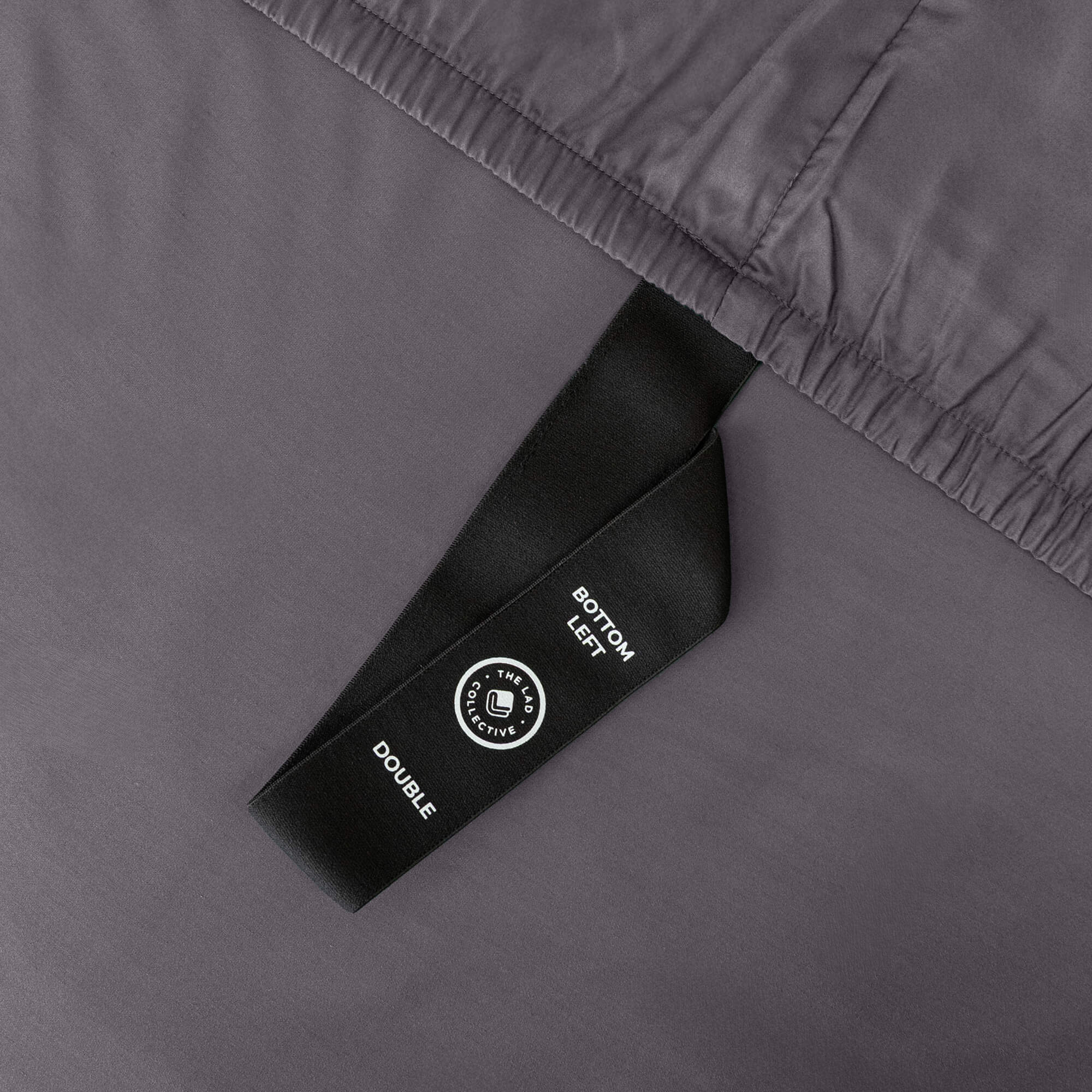 Close up of corner strap of fitted sheet in gray coloured bedding