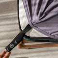 Person adjusting a gray fitted sheet with a black strap on a gray surface