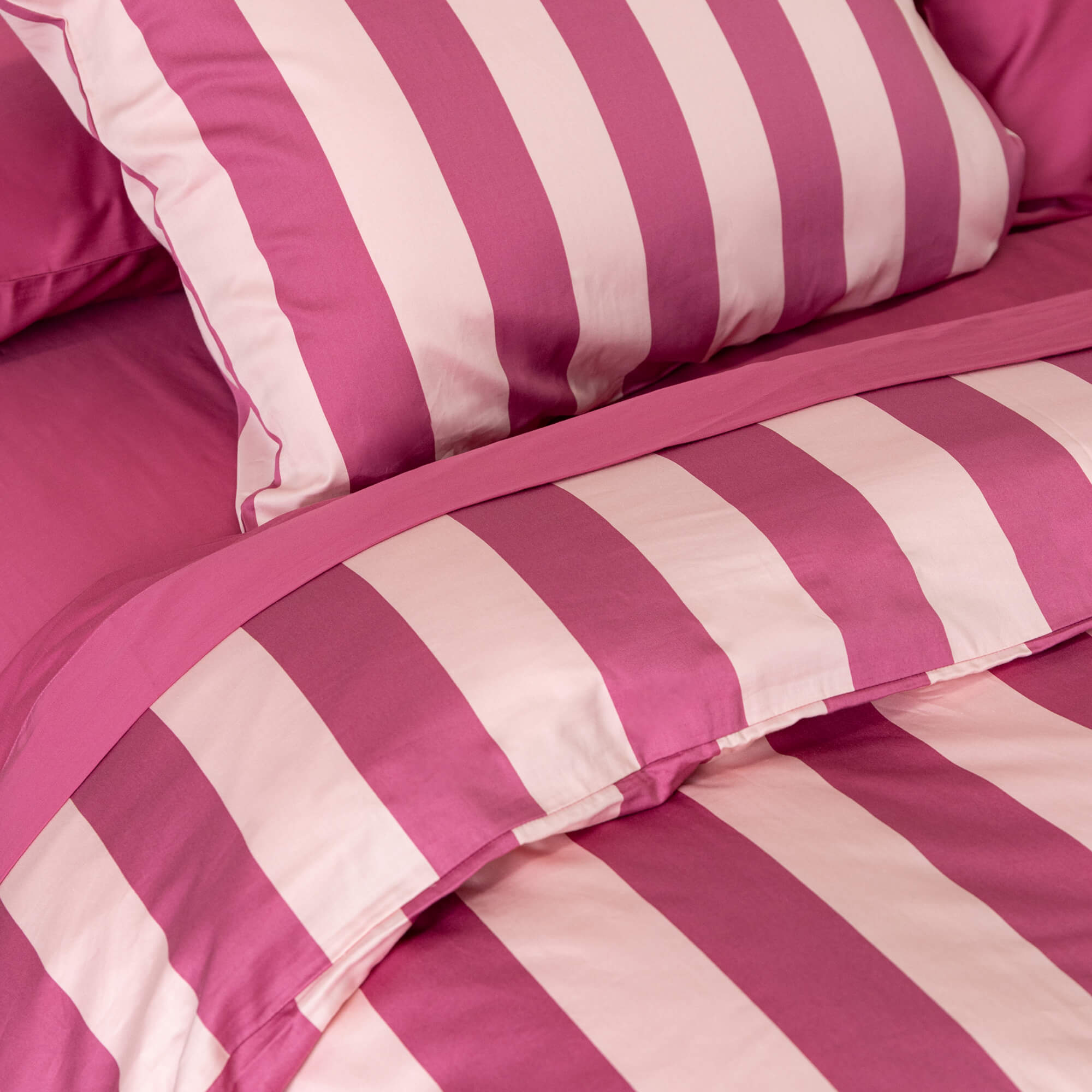 Close-up details of a raspberry pink stripe duvet cover set on a bed.