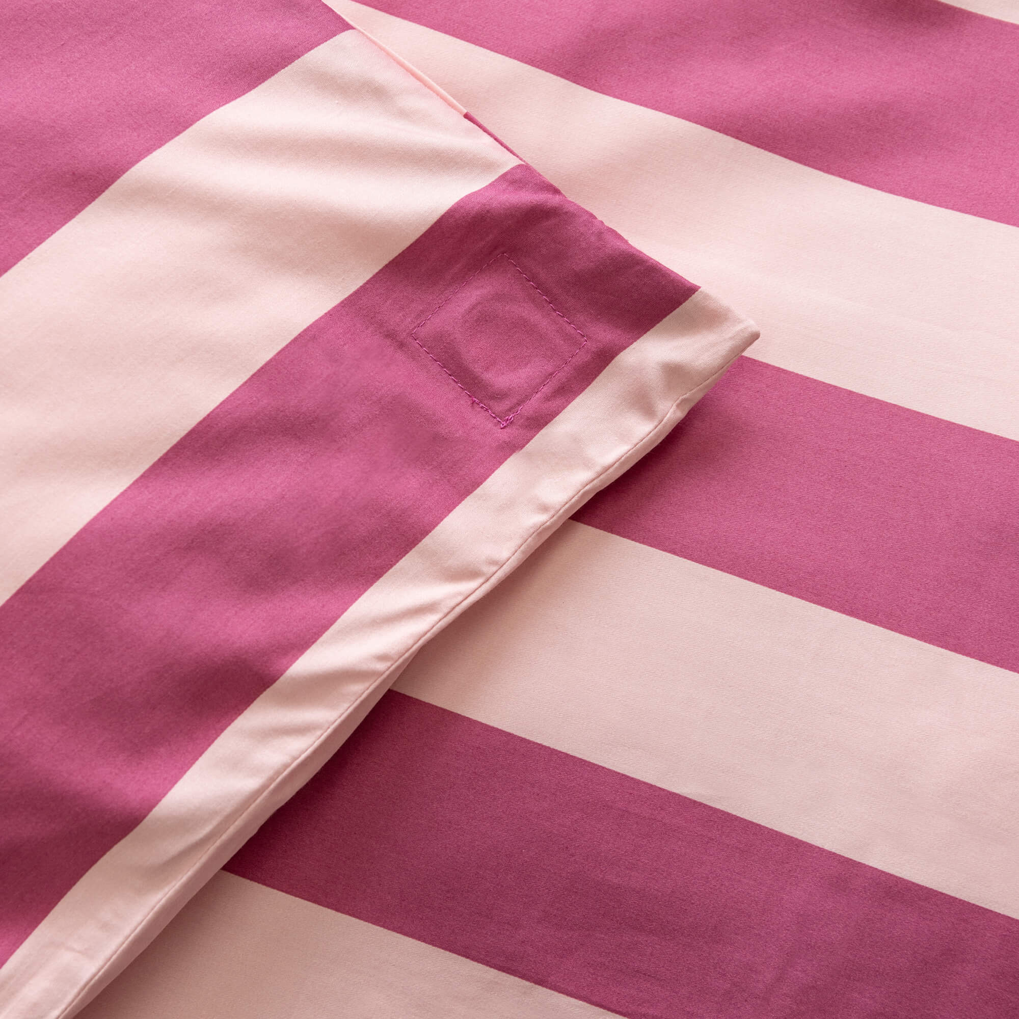 Close up of raspberry pink stripe duvet cover magnetic corner. 