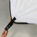 Person holding a black strap with a brand logo on a white mattress.