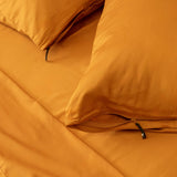 Close up of orange pillowcases with zipper detail on orange bedspread.