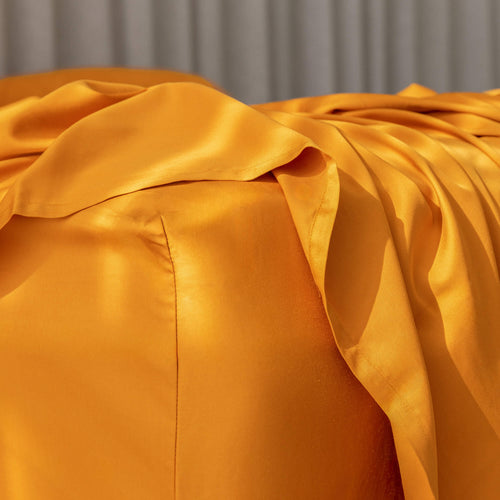 Orange bedding fitted sheet on corner of mattress.