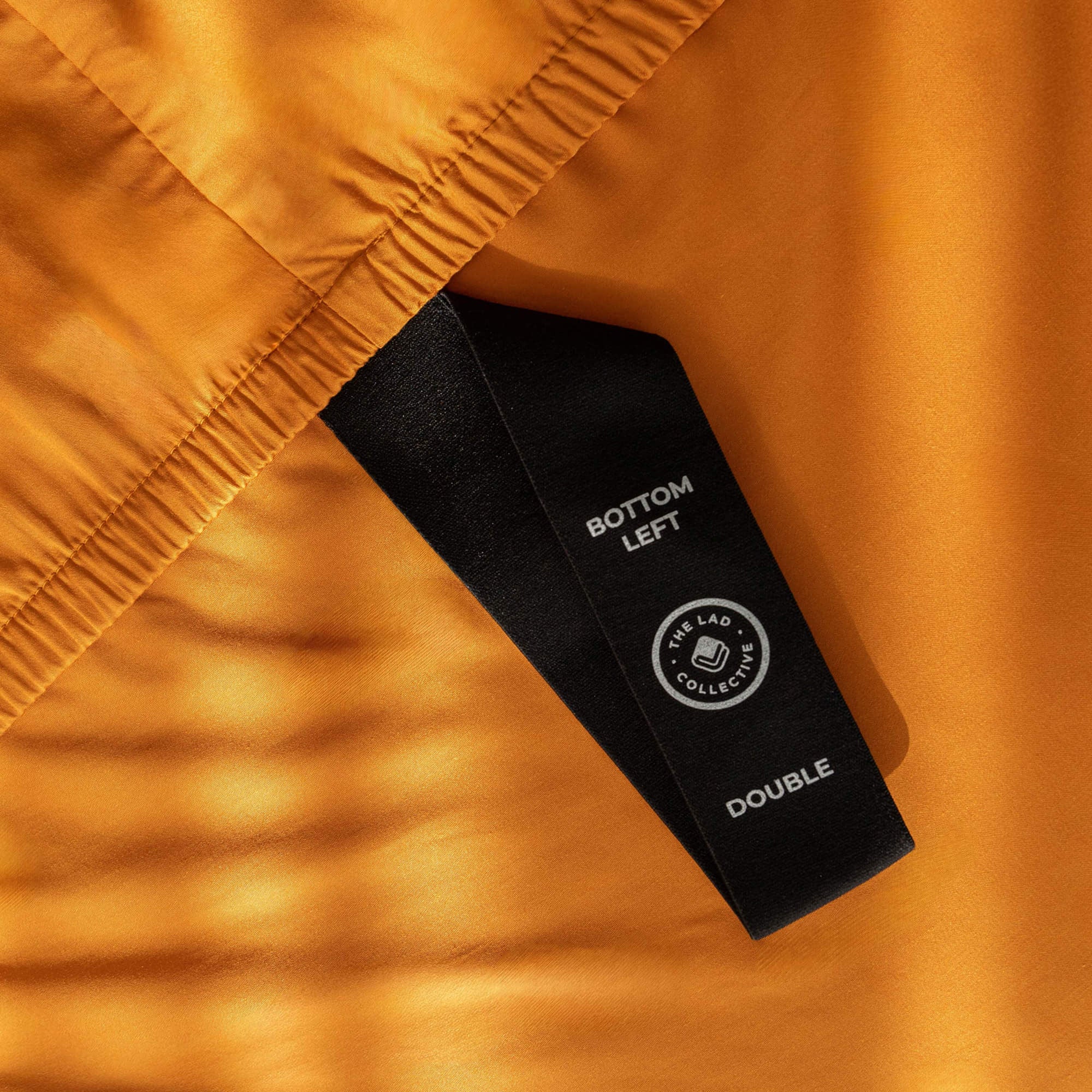 Close up of labeled loop corner strap on orange bedding.