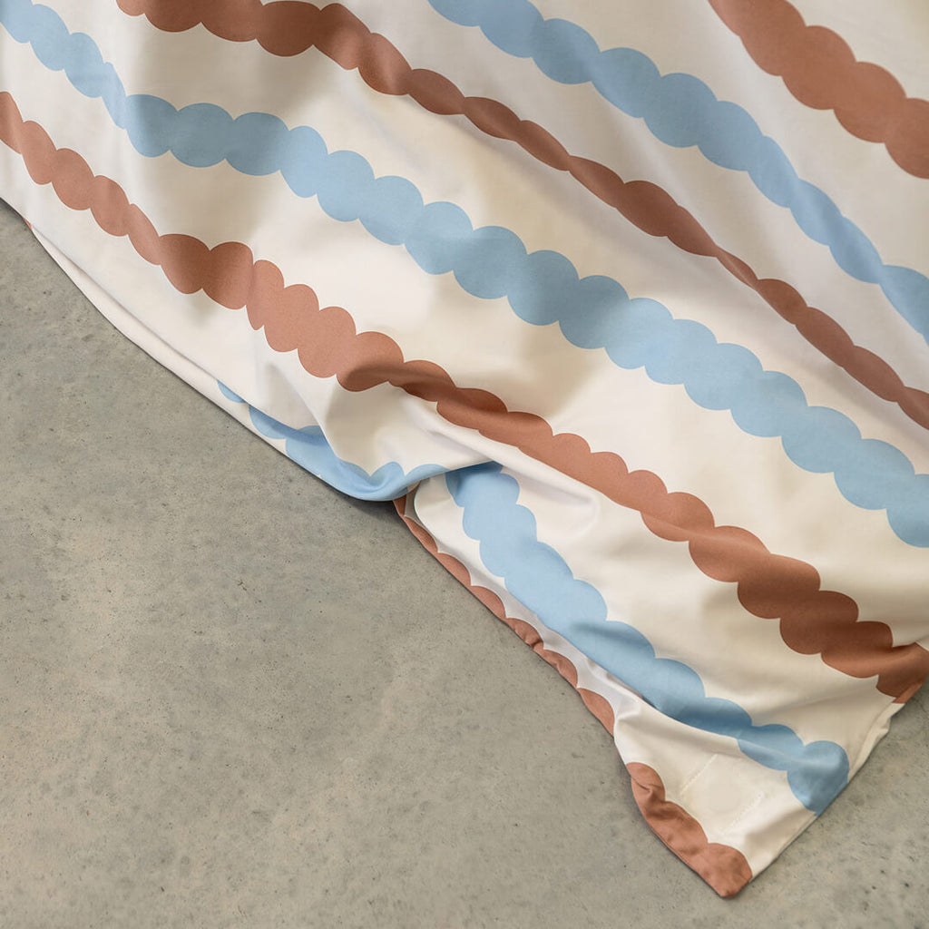 Close-up of a fabric with brown and blue striped pattern on a grey surface.