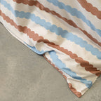 Close-up of a fabric with brown and blue striped pattern on a grey surface.