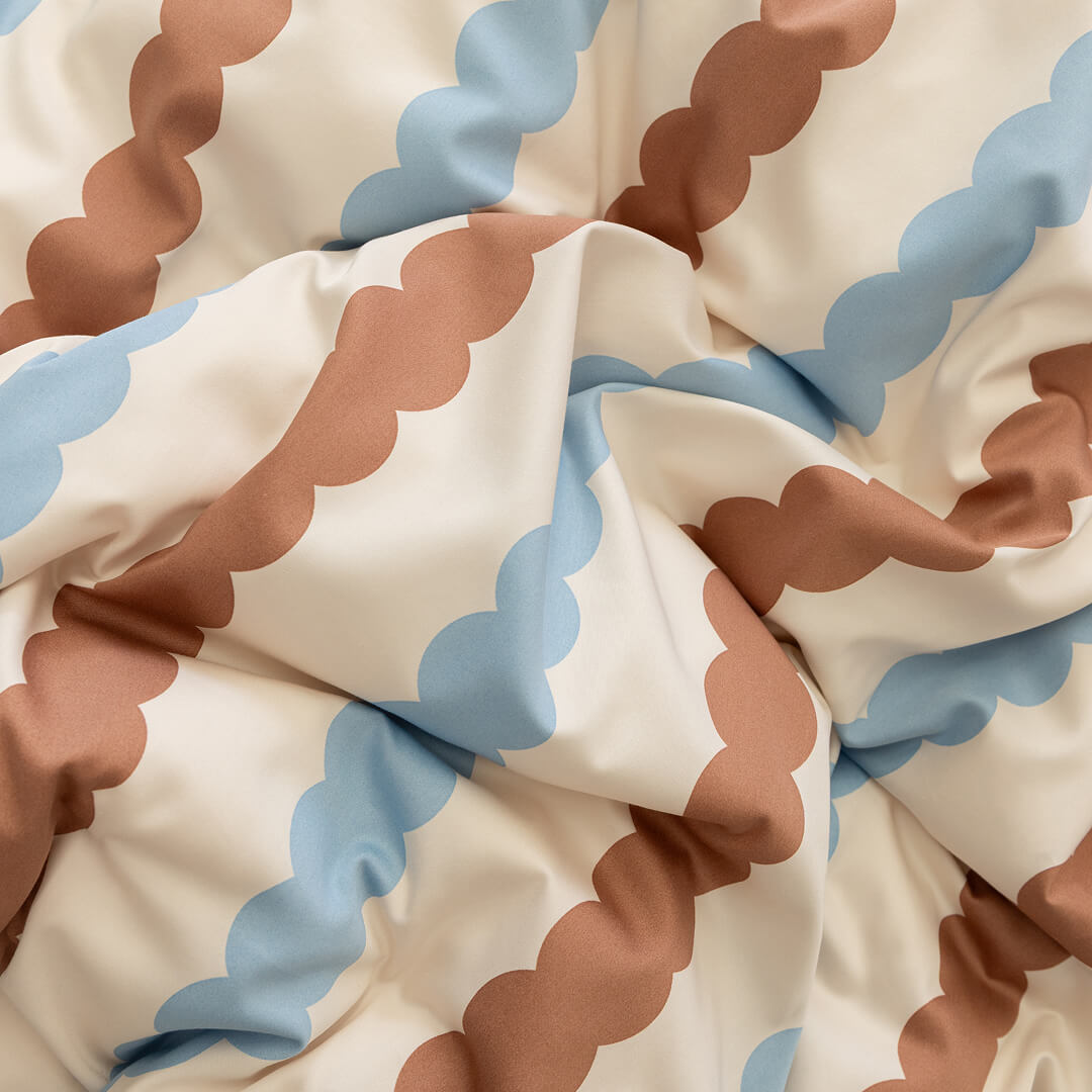 Close-up of fabric with wavy brown and blue pattern on beige background