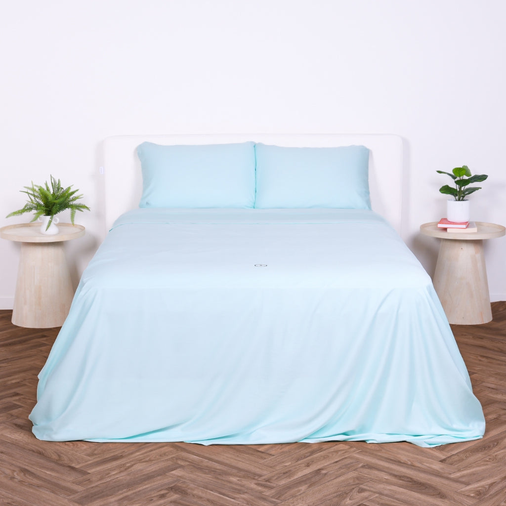 Front view of a bed with Riviera Blue sheet set and two pillows, styled with minimal decor.