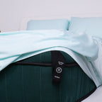 Corner of bed with Riviera Blue sheet tucked under mattress, showcasing labeled strap for fit guidance.