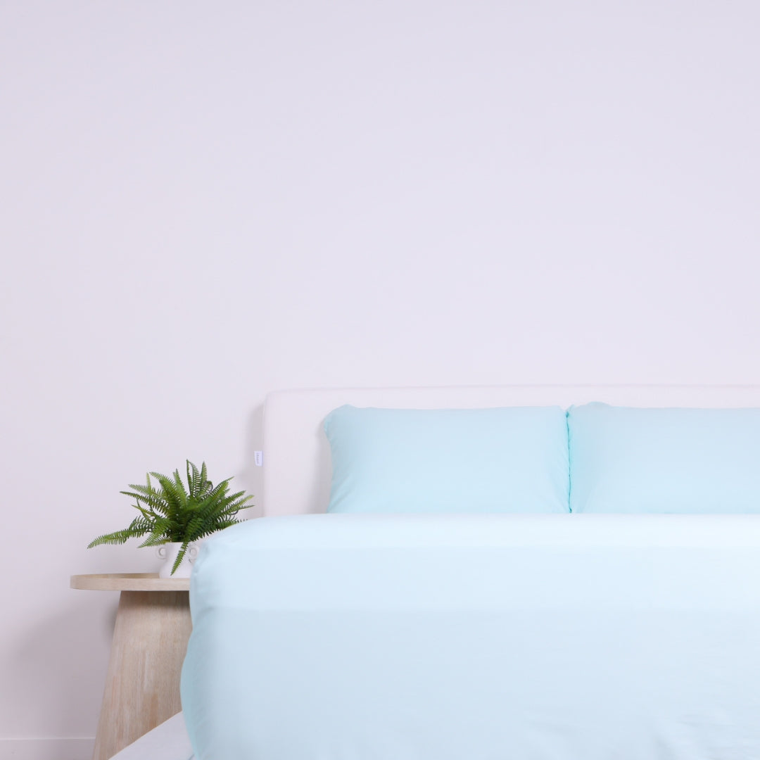 Symmetrical view of a bed with neatly tucked Riviera Blue bedding and matching pillows.