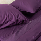 Close-up of purple bedding with two pillows on a bed.