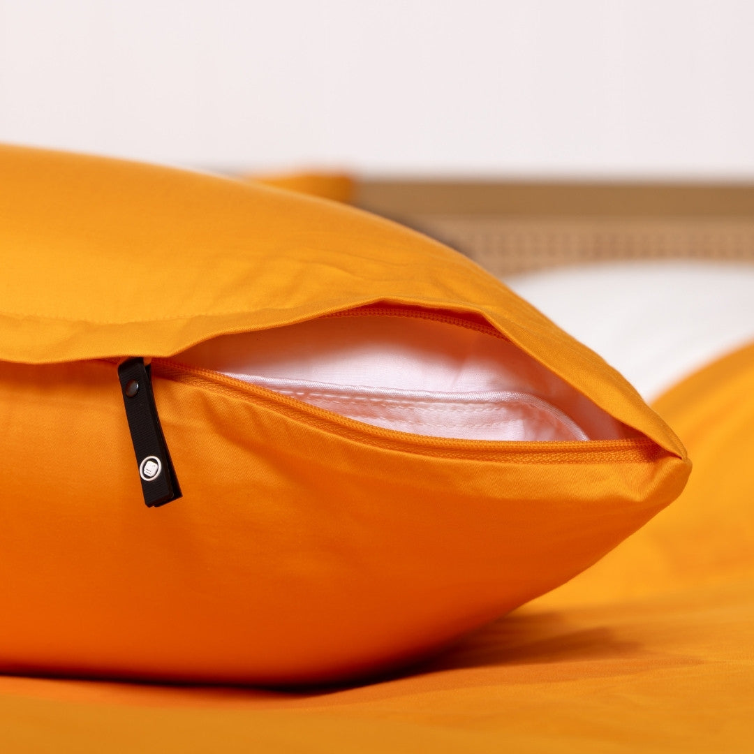 Close-up of an orange pillow with a clear window on a bed.