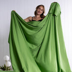 Woman displaying green TLC 3.0 Colorado sheet in modern bedroom setting. 