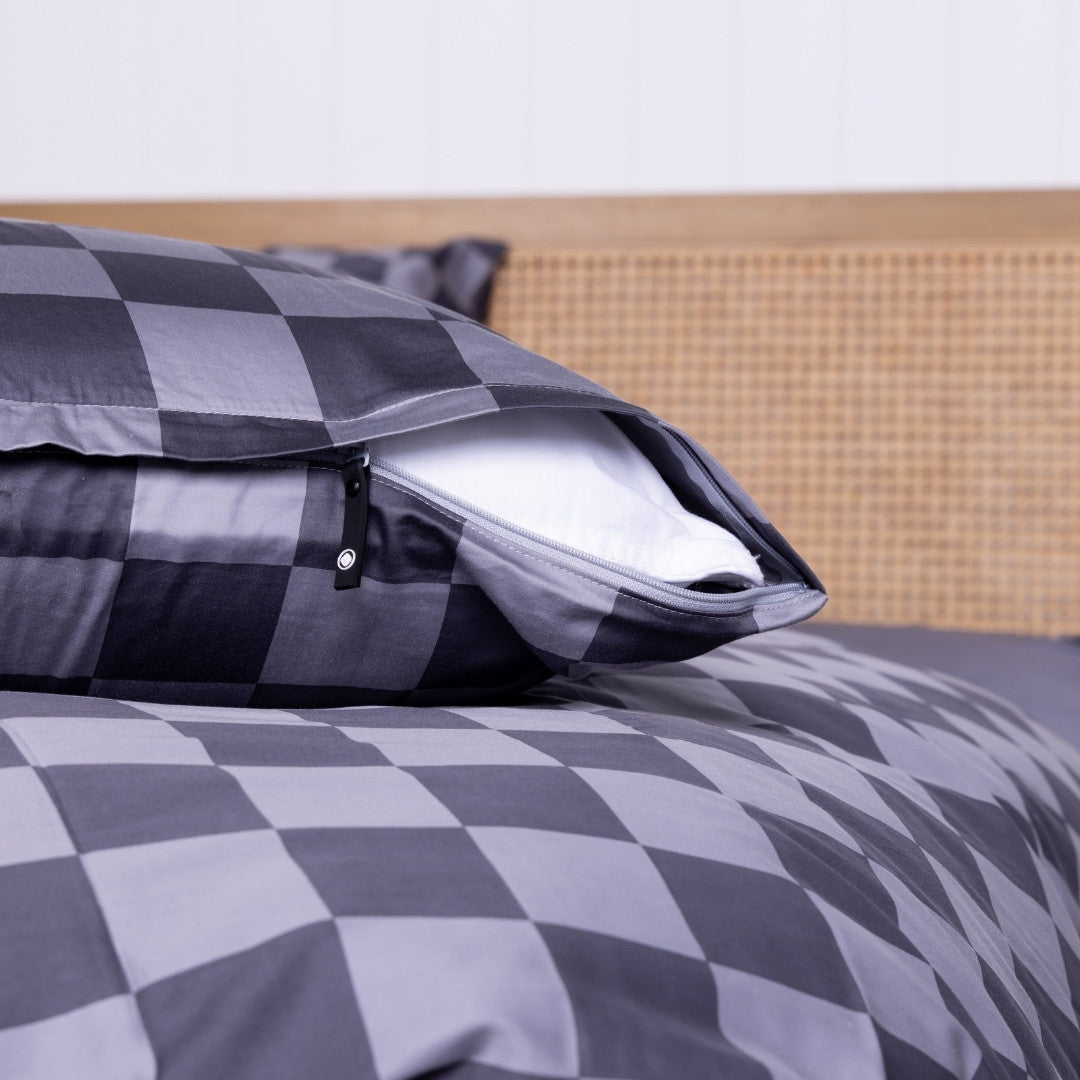 Gray checkered pillowcase on pillow, showcasing invisible zipper on a bed with a neutral headboard.