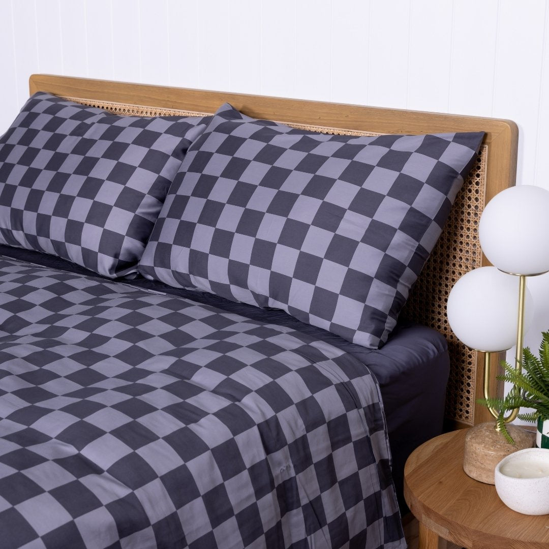 Checkered duvet cover set on a bed with a wooden headboard and side table.