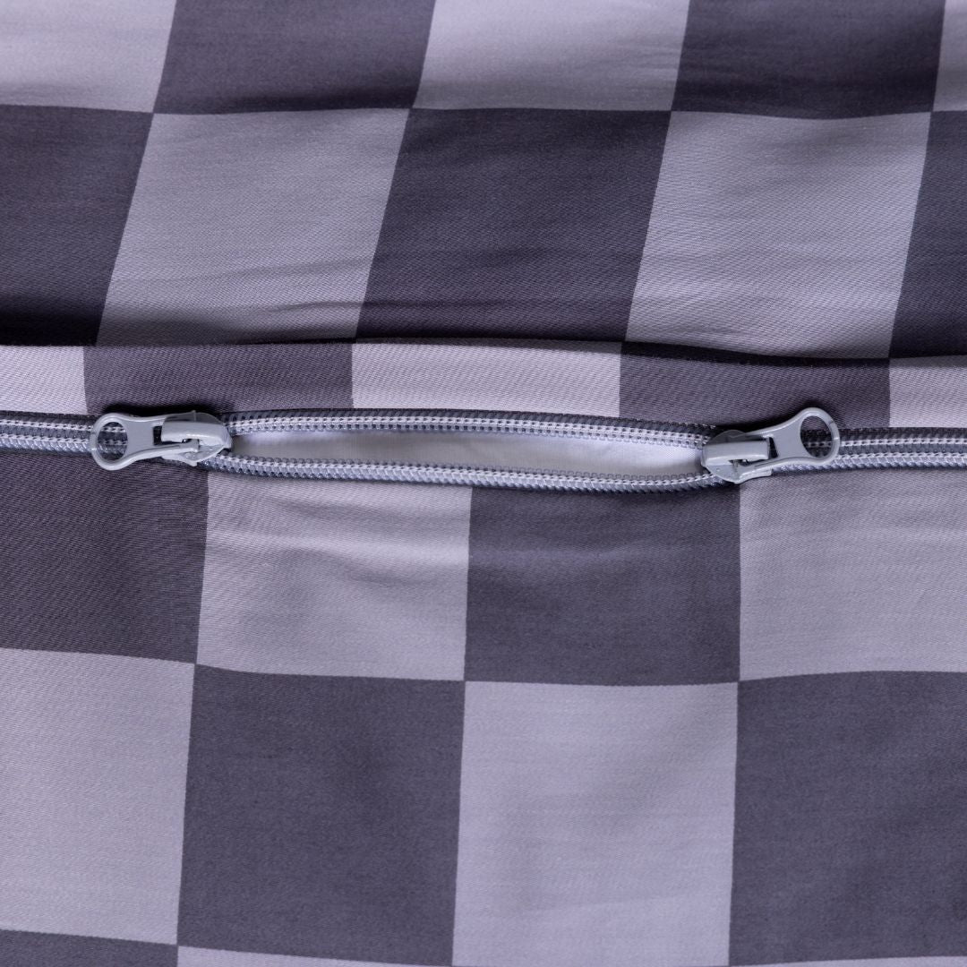 Close-up of a checkered fabric with a zipper on a gray background.