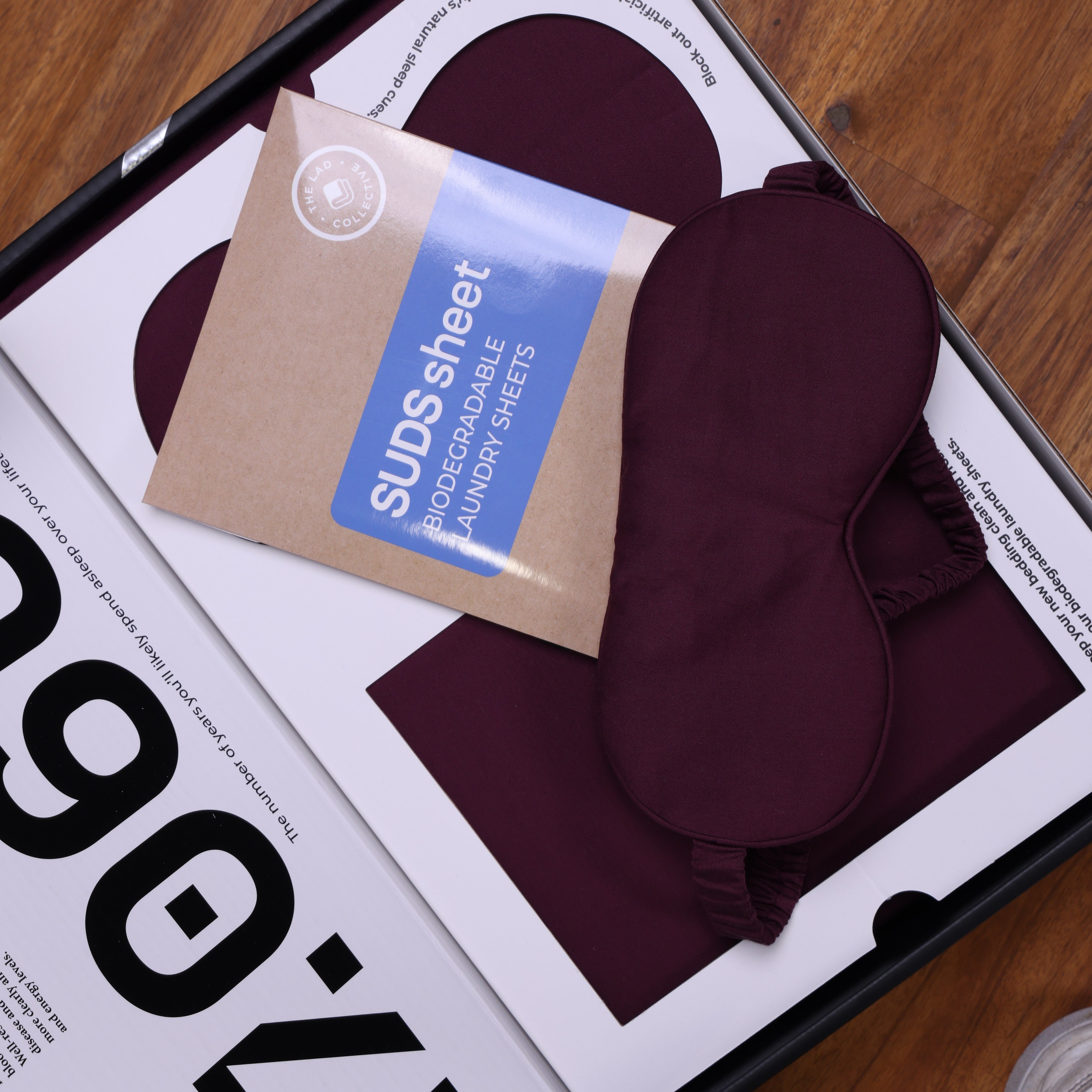 TLC 3.0 Bedding Set packaging showing burgundy eye mask and biodegradable laundry Suds Sheets.