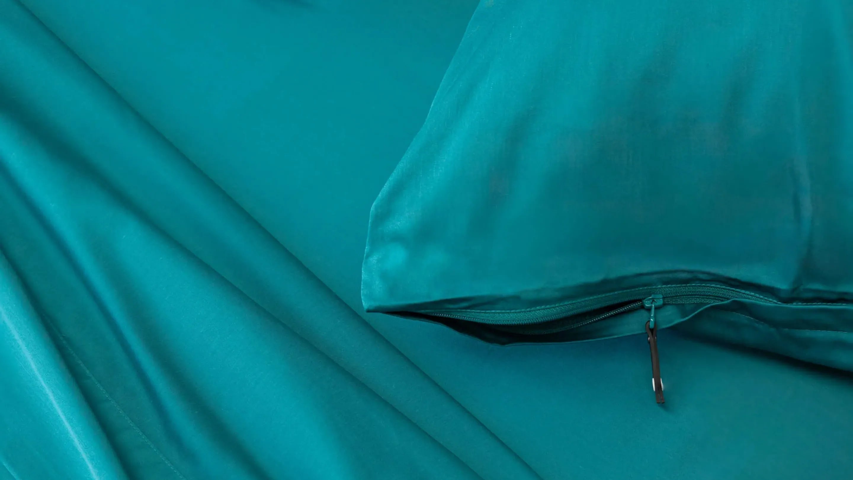 Teal satin pillowcase on a teal fabric background