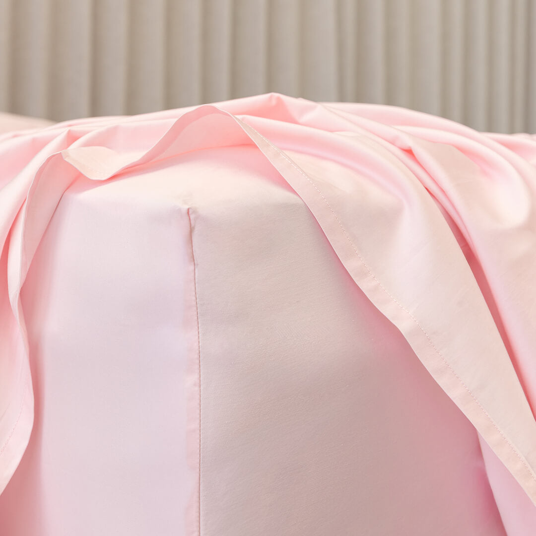 Close-up of a pink fitted sheet corner fabric on bed.