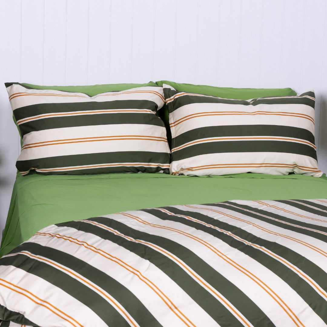 Striped green and white bedding set with pillows on a bed.