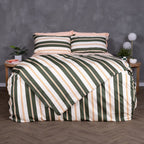 Front-facing view of a bed dressed in the Lake Tahoe Magnetic Clip & Zip Duvet Cover. The bold striped design in green, cream, and amber commands attention, with matching pillowcases and light peach sheets peeking through at the top.