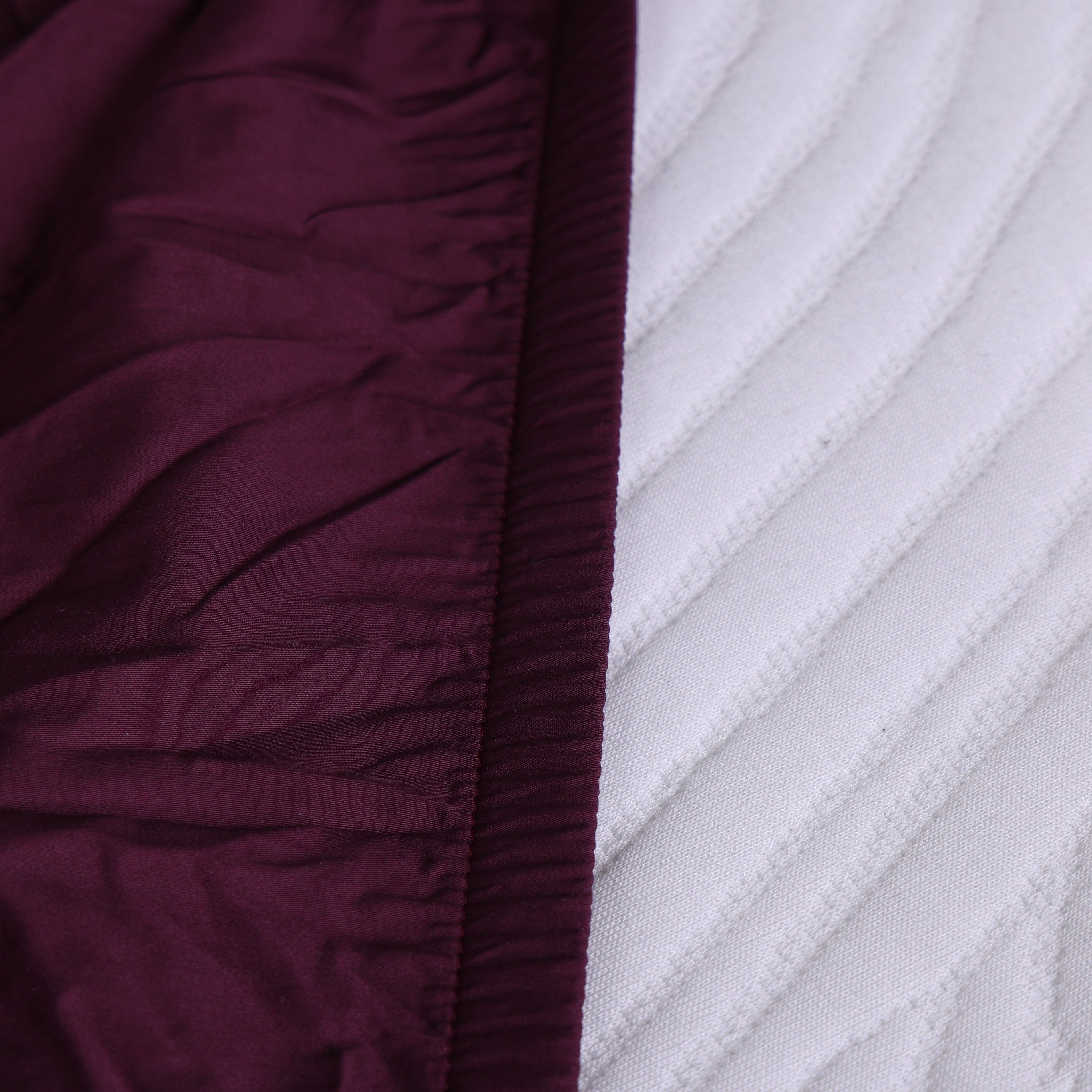 Close-up of New England fitted sheet corner with elastic edge on white mattress.