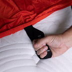 Close up of hand pulling the labeled loop corner strap on Red rock fitted sheet.