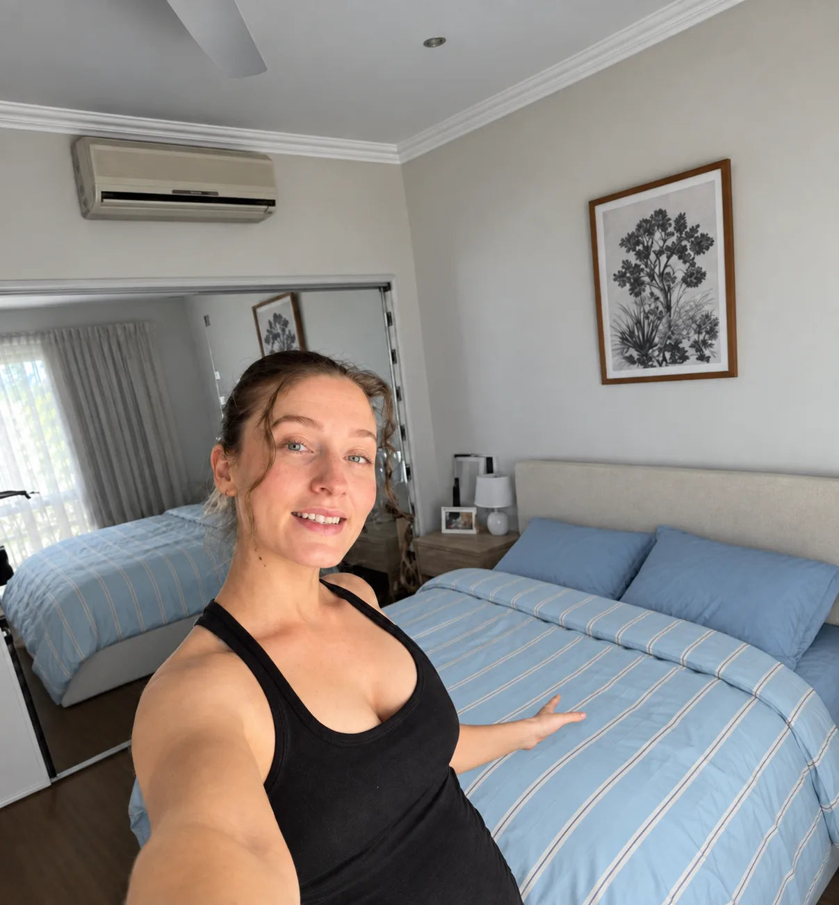 Laura beside blue pillows and a striped duvet in a bedroom styling illustration
