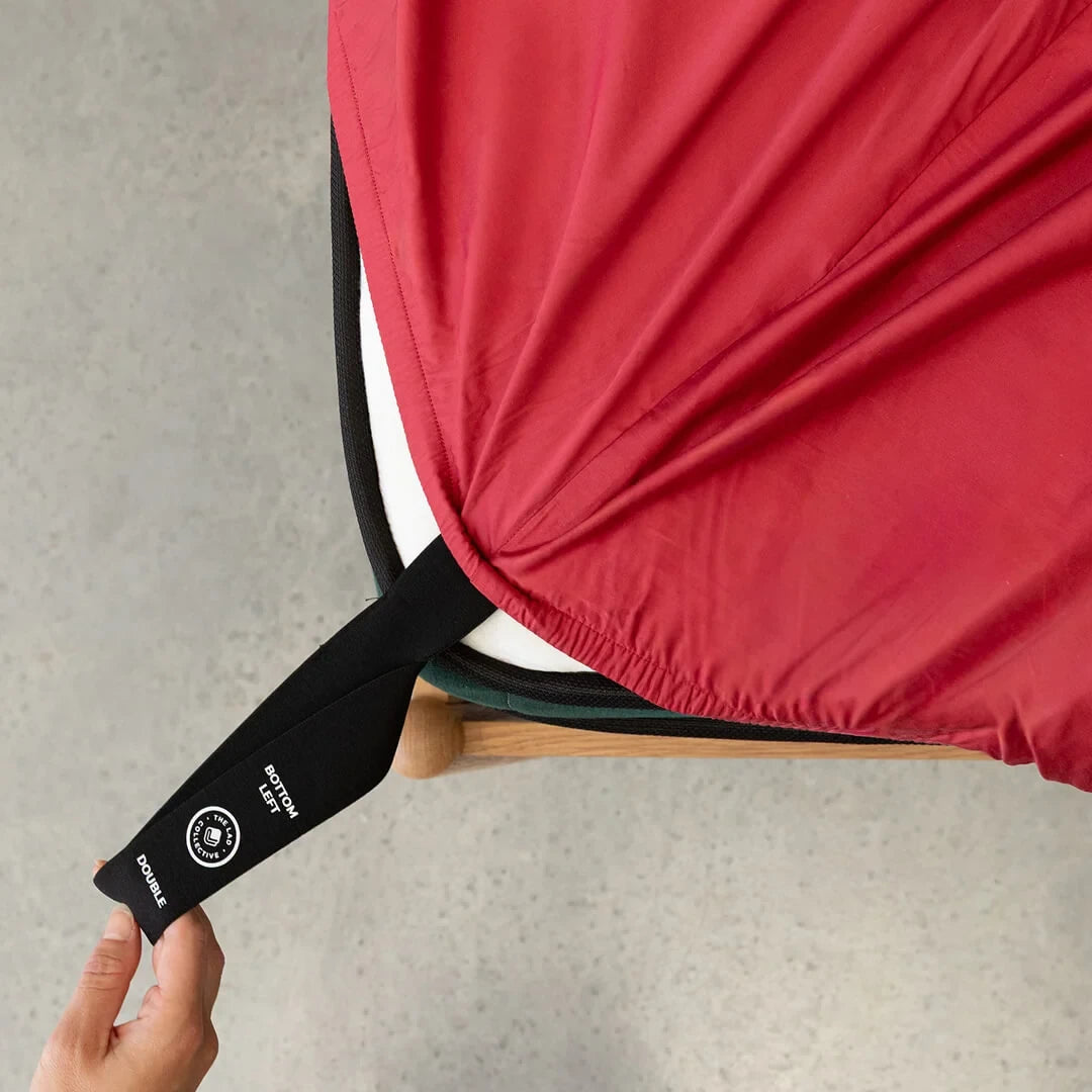 Hand pulling the fitted sheet corner loop over a mattress