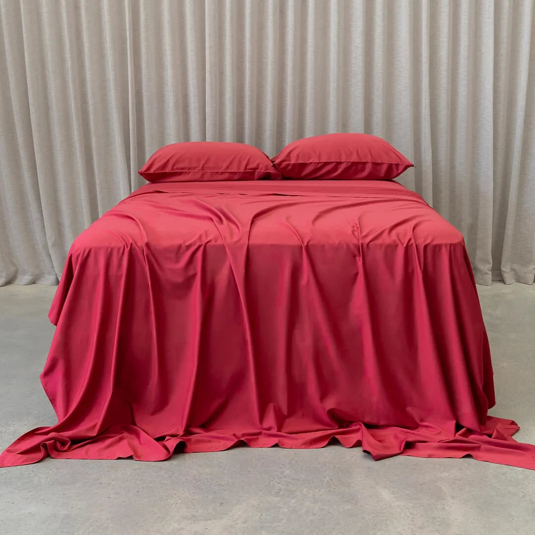 A neatly made bed with red Napa sheets