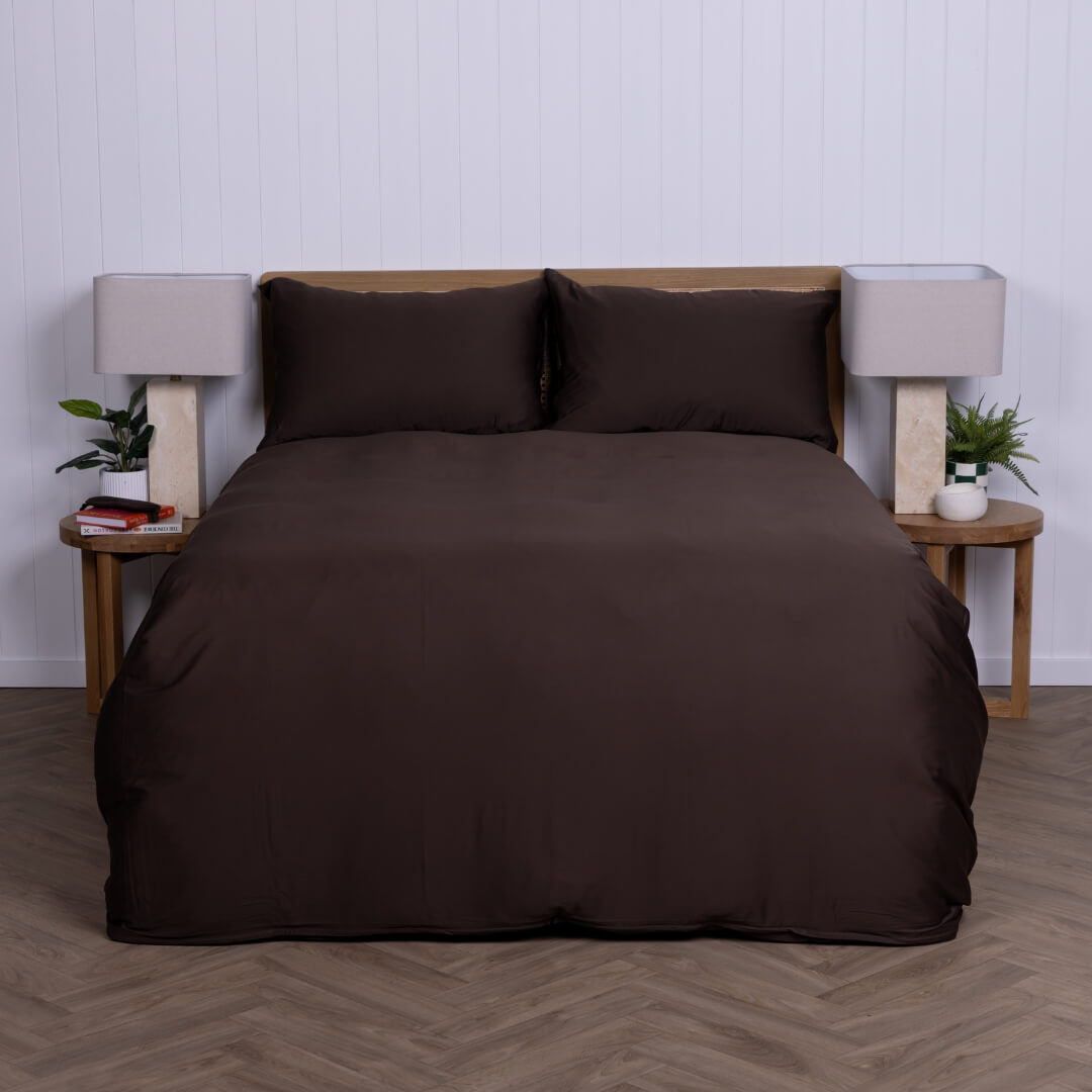 Brown duvet cover set on a bed with matching pillows against a white wall.