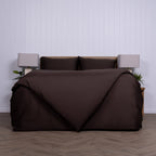 Brown bedspread on a bed with a white wall and wooden floor in the background