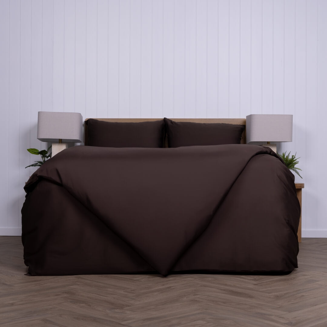Brown bedspread on a bed with a white wall and wooden floor in the background