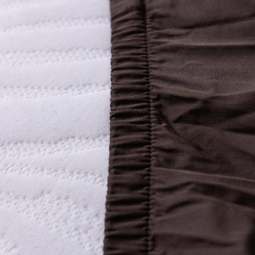 Close-up of white quilted fabric and brown textured fabric from fitted sheet.