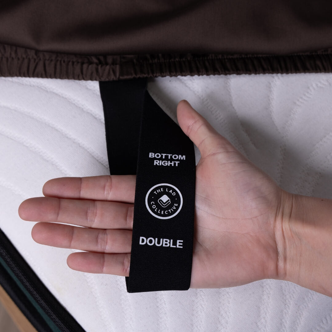 Hand holding a black tag labeled 'Bottom Right Double' on a mattress.