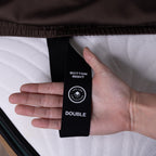 Hand holding a black tag labeled 'Bottom Right Double' on a mattress.